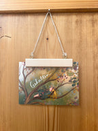 Postkarte „Gehalten.“ | Baumbotschaften 2: Ein liebevoll illustriertes Affirmationsmotiv über Geborgenheit und Trost.